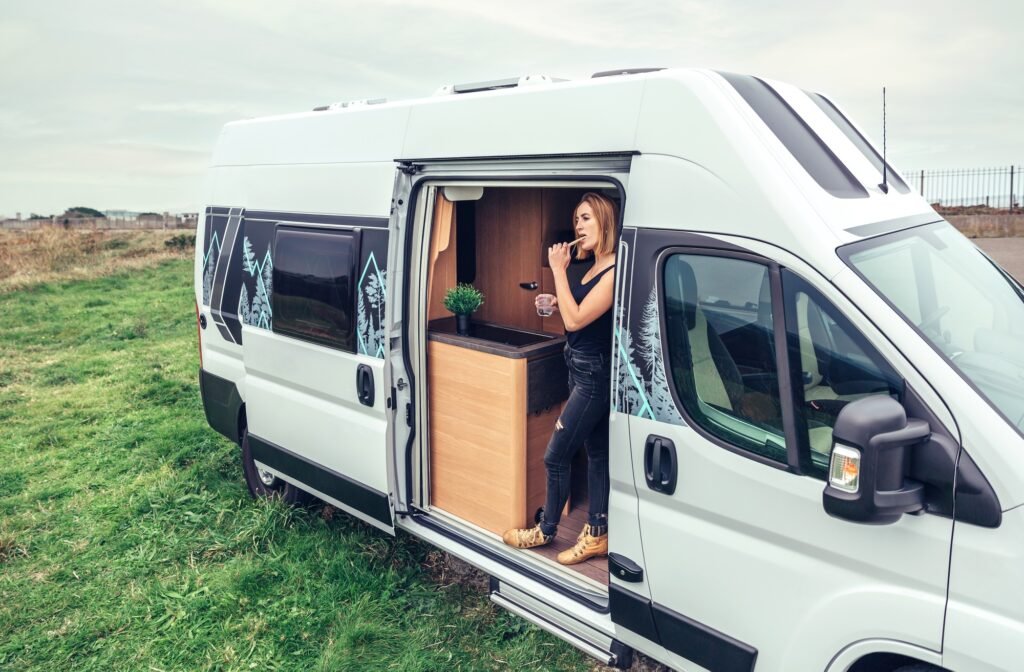 Woman brushing teeth in the morning at the door of her campervan
